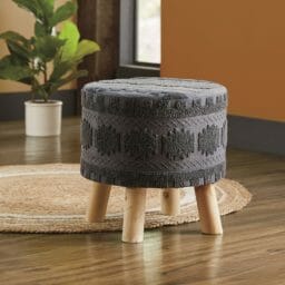Drea Upholstered Stool on round natural rug against orange wall