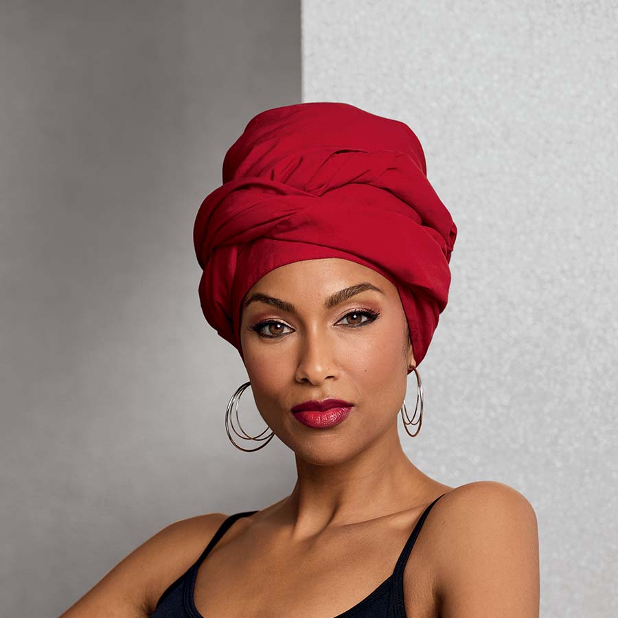 African American woman wearing solid red headwrap and triple hoop earrings with black top.