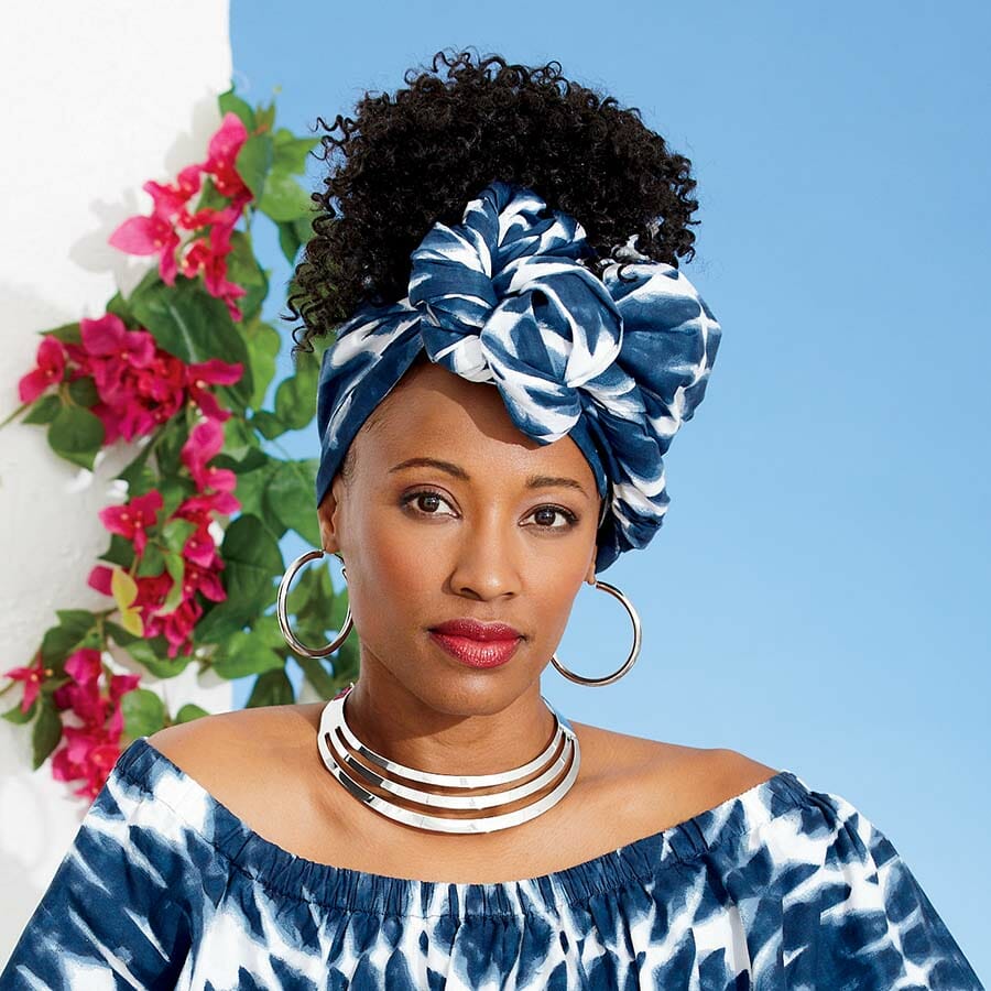 African American woman wearing blue and white headwrap with hoop earrings, necklace and matching outfit.