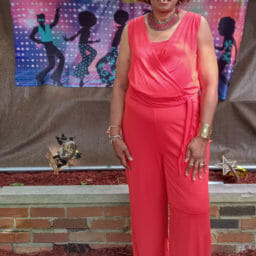 photo of a woman in a jumpsuit in front of a birthday celebration sign.