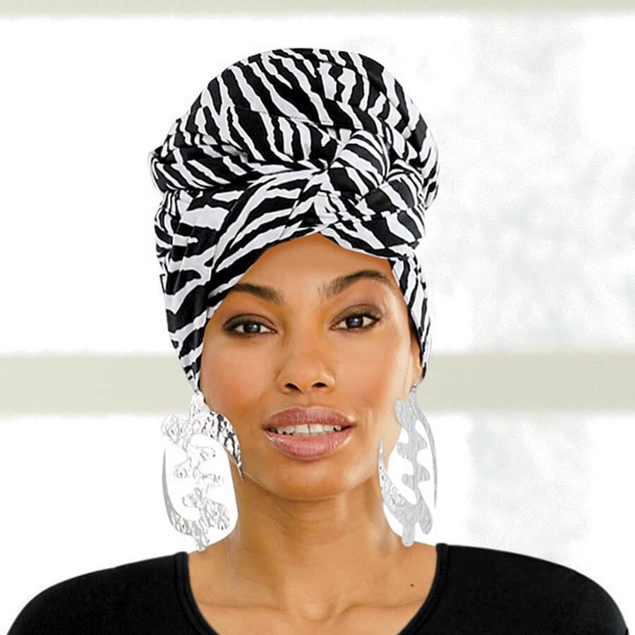 African American woman wearing a black and white zebra print headwrap, black top, and silver earrings.