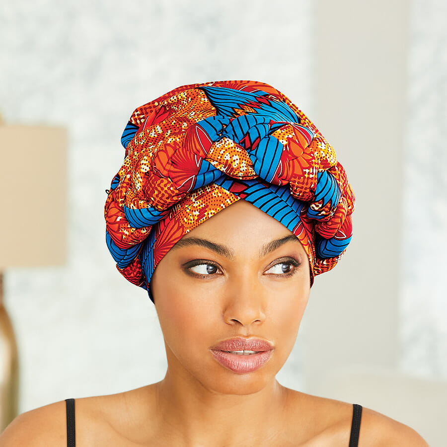 African American woman wearing blue, red, orange, yellow and white headwrap with black top.