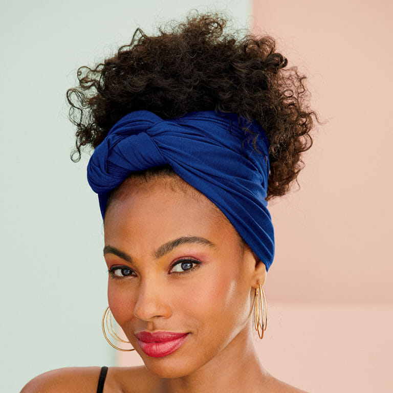 African American woman with blue headwrap and multi-tone triple hoop earrings.