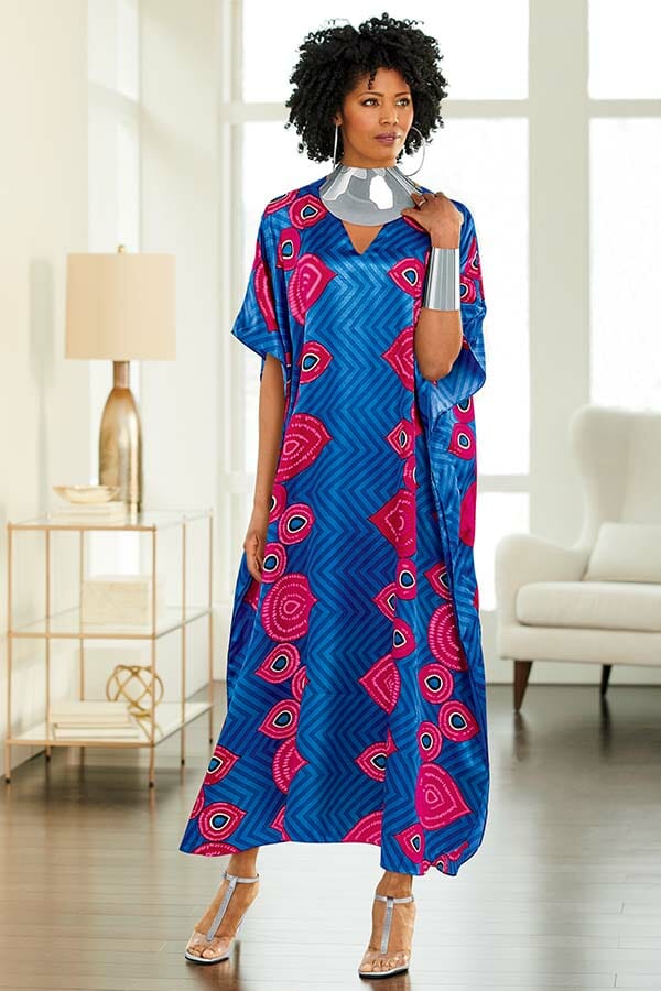 African American woman wearing blue, pink and white chevron caftan with v-neck and silver cuff bracelet, silver collar necklace and silver hoops.                     