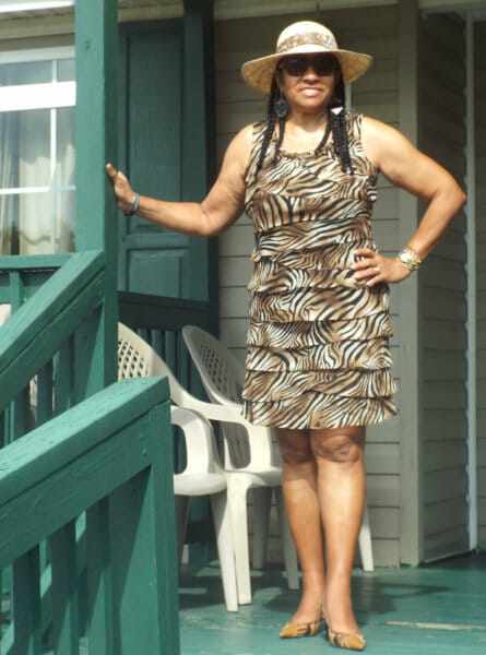 woman standing on porch steps in dress with a printed design.