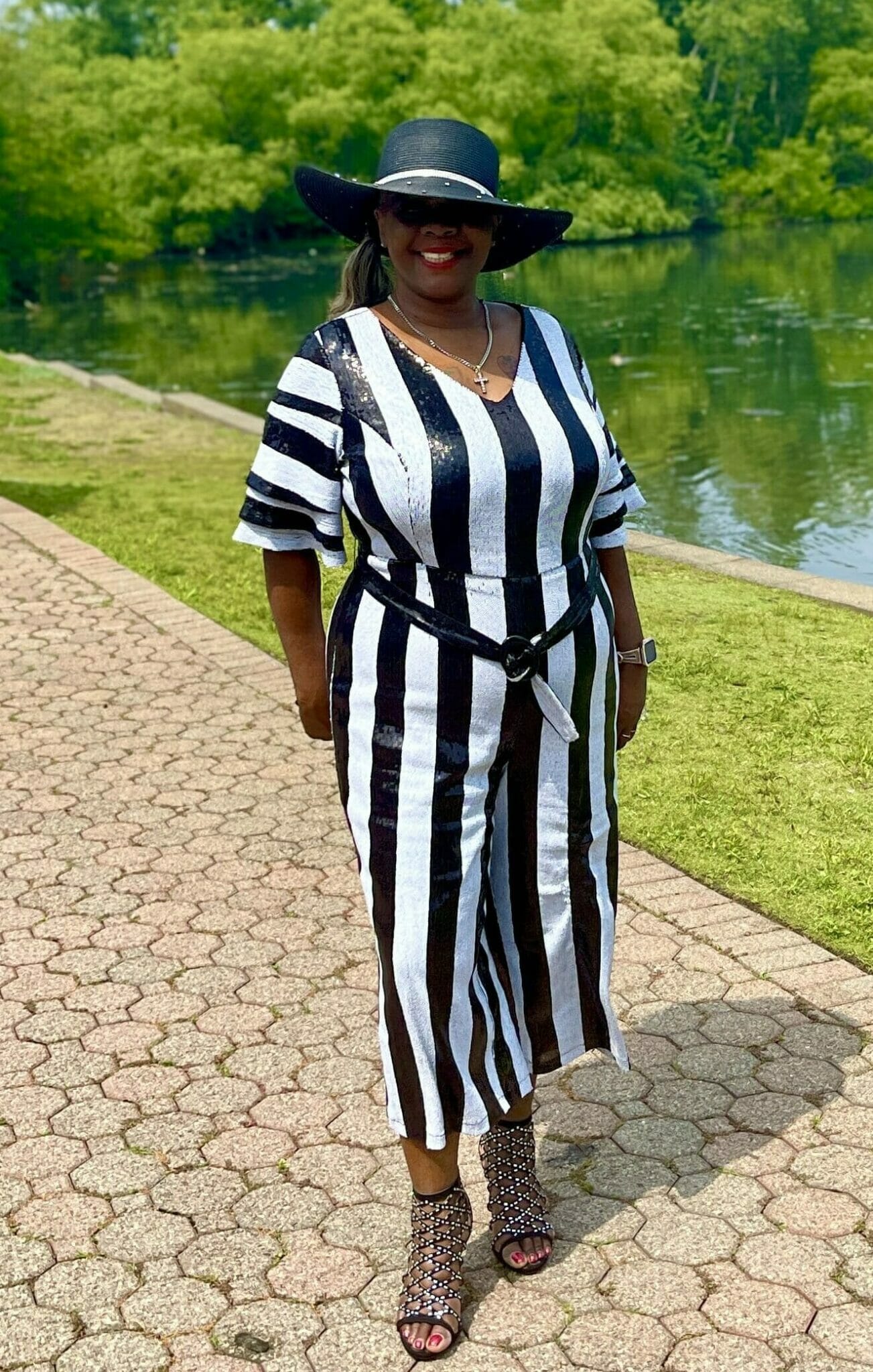 Black woman wearing black and white striped dress with black hat.