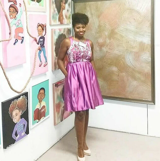 Black woman posing in front of her art work