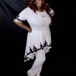 Black woman wearing white top with white pants.
