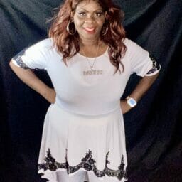 Black woman wearing white top with white pants.