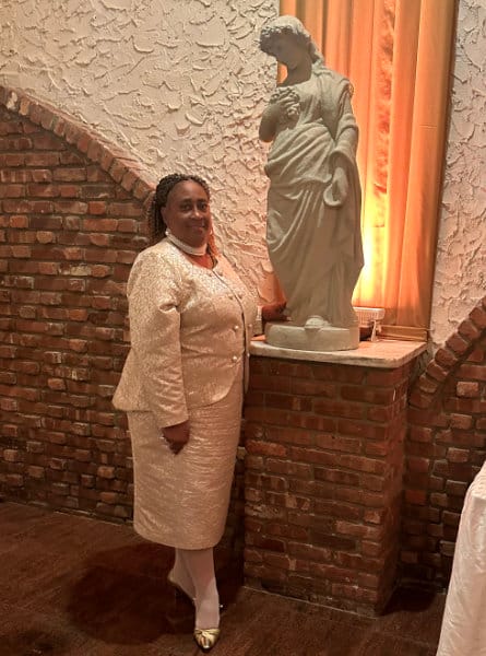 Woman in a white dress suit standing next to a statue.