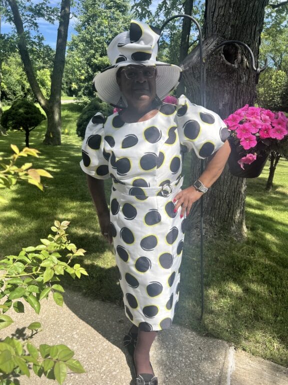 Woman posing in polka dot dress with a matching hat.